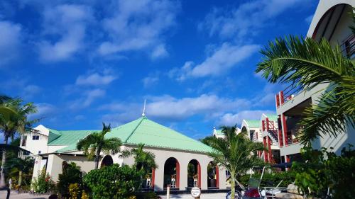 a building with a green roof and palm trees at Tres Cocos Resort in San Pedro