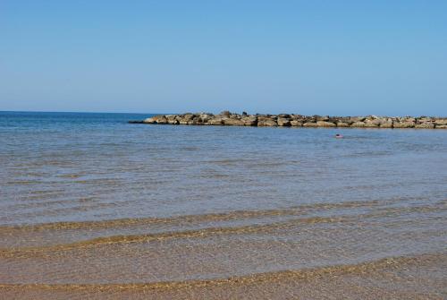 a beach with a group of rocks in the water at Lido Apartment in Donnalucata