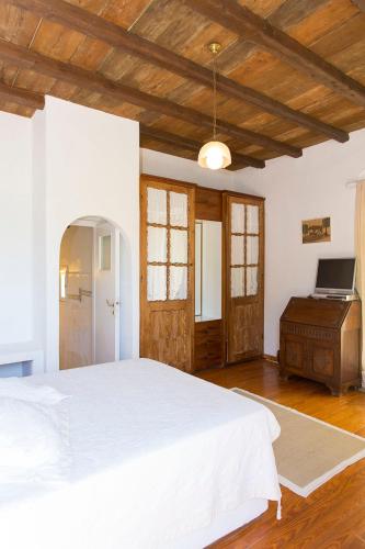 una camera da letto con un letto bianco e un soffitto in legno di Traditional Mykonian Villa a Ornos