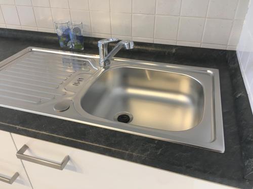 einem Spülbecken aus Edelstahl mit einem Wasserhahn in der Küche in der Unterkunft Apartma Bluemarin in Koper