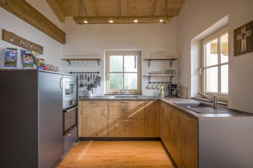 a kitchen with wooden cabinets and a stainless steel refrigerator at Reiterbauer Chalets & Ferienwohnungen in Kirchberg in Tirol