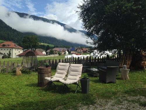 a pair of chairs sitting in the grass near a fence at Apartments Resi in Rasùn di Sotto