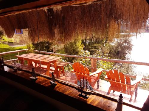 a porch with two chairs and a table on a deck at Cabañas Yukatan Lago de Tota in Tota