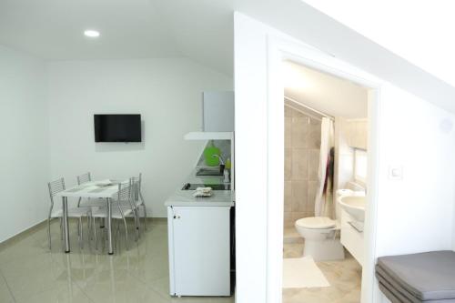 a white bathroom with a toilet and a table at Apartmani "ROSHU" in Soko Banja