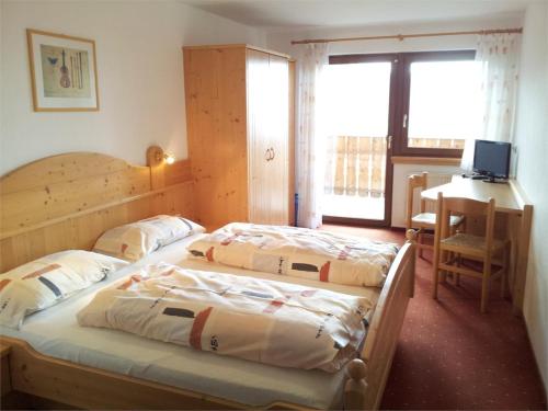 two beds in a room with a desk and a computer at Gasthof Walde in Rifiano