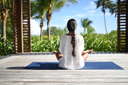 a woman sitting in a yoga pose on a dock at Unico Hotel Riviera Maya Adults Only in Akumal