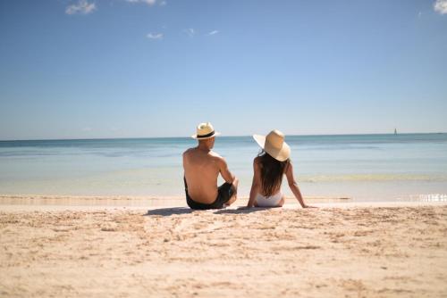 mężczyzna i kobieta siedzący na plaży w obiekcie Unico Hotel Riviera Maya Adults Only w mieście Akumal