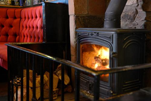 a wood stove with a fire in a room at The Farmers Inn in Dumfries