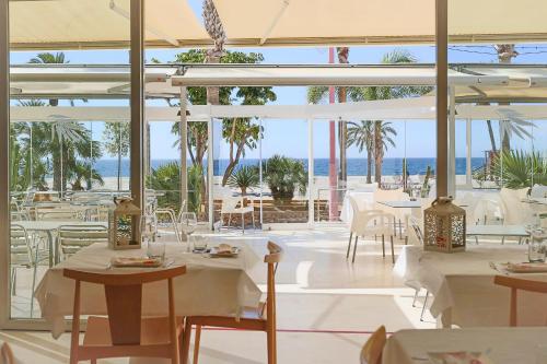 a restaurant with white tables and chairs and the ocean at Hotel Las Palmas in Carboneras