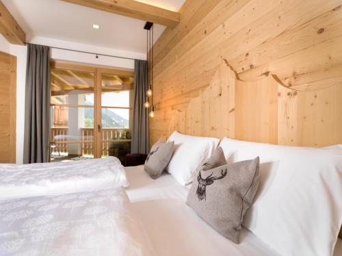 two white beds in a room with wooden walls at Chalet Novalis in San Candido