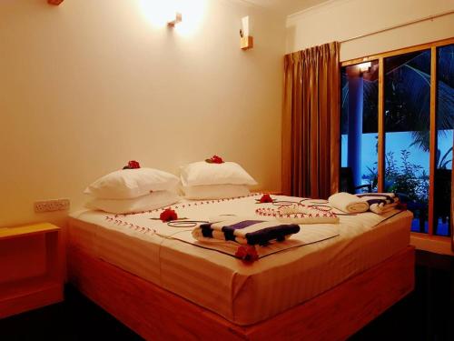 Thoddoo Beach Holiday Inn في ثودو: غرفة نوم مع سرير مع زهور حمراء عليه