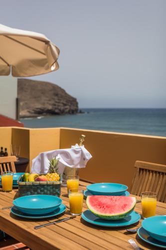 a wooden table with plates of food and fruit on it at Ocean View Penthouse II in Gran Tarajal