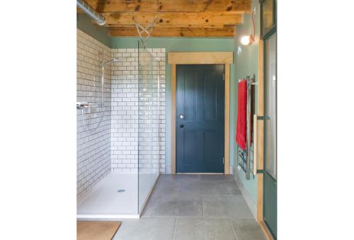 a bathroom with a shower and a blue door at Le Moulin du Mottay in Évran