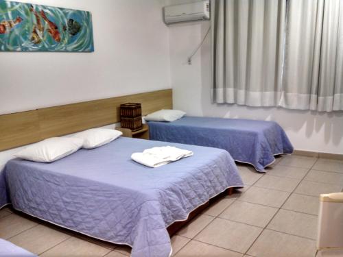 two beds in a room with purple sheets at Hotel Diamantina - By UP Hotel - em Guarapari in Guarapari