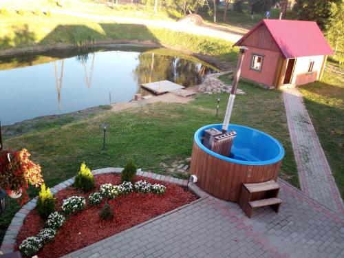 a hot tub next to a small house next to a lake at Holiday home Tūjas in Krāslava