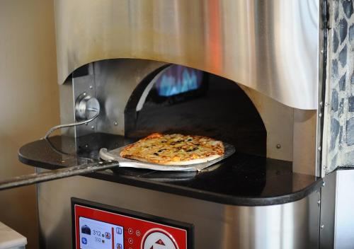 a pizza is being cooked in an oven at Euphoria Batumi Convention & Casino Hotel in Batumi