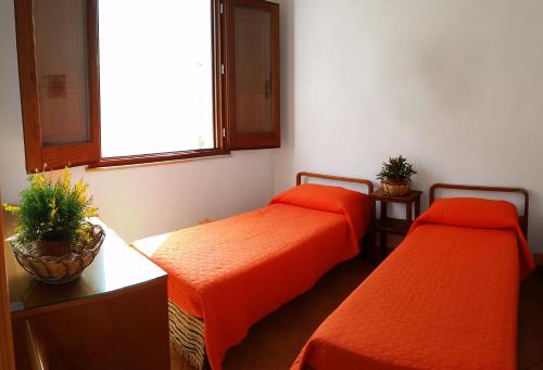カステッルッツォにあるMastromario Apartmentsのオレンジのシーツが備わるベッド2台(1室あたり)