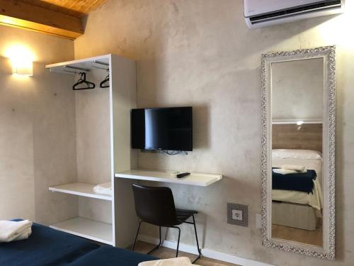 a room with a mirror and a chair and a television at Casita del Abuelo Mayorga in Plasencia