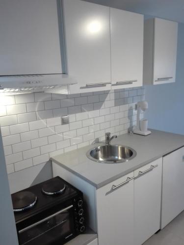 a white kitchen with a sink and a stove at Blue Studio in Nea Moudania