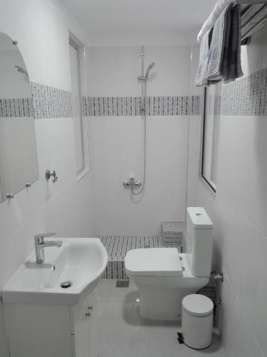 a white bathroom with a toilet and a sink at Blue Studio in Nea Moudania