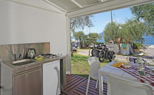 an outdoor kitchen with a table and a view of the water at Camping Spiaggia D' Oro Torri in Torri del Benaco