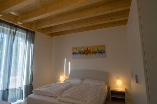 a bedroom with a bed with two lamps and a window at Val Mora Bio Apartments in Garda