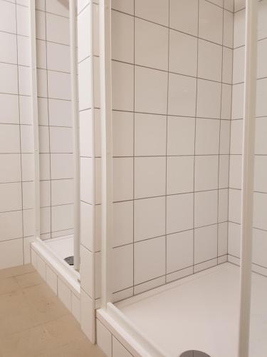 a white tiled bathroom with a shower with a mirror at Chatky Skalní mlýn Adršpach in Adršpach