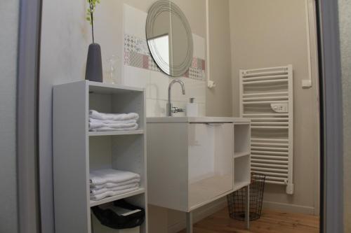 W białej łazience znajduje się umywalka i lustro. w obiekcie Le Logis GOUT - L'Oustal w Carcassonne