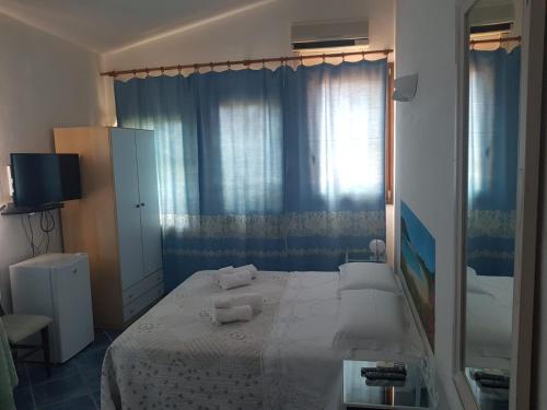a bedroom with a large white bed with blue curtains at Bed and Breakfast da Gigi e Antonella in Porto Rotondo