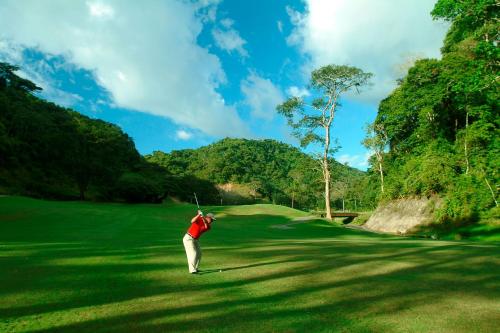 
a man standing on top of a lush green field at Los Sueños Marriott Ocean & Golf Resort in Jacó
