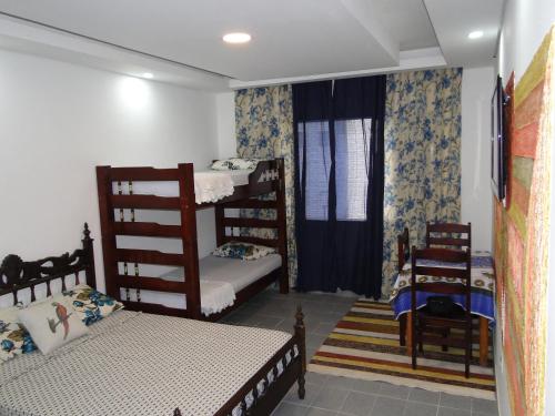 a bedroom with two bunk beds and two chairs at Edificio Edmeia in Praia Grande