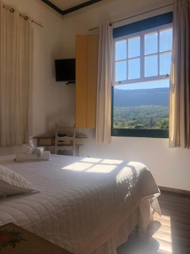 a bedroom with a bed and a window at Pousada Vovô Chiquinho in Tiradentes