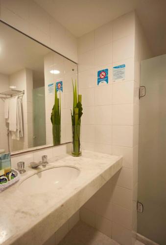 a bathroom with a sink with a mirror and a vase at Hotel Euro Suíte Recife Boa Viagem By Nacional Inn in Recife