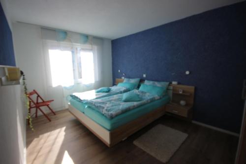 a bedroom with a bed and a blue wall at Ferienwohnung Loreley in Lierschied