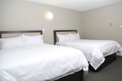 two beds in a hotel room with white sheets at Valemount Vacation Inn in Valemount