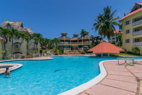 una piscina en un complejo con palmeras y edificios en Hillview At Mystic Ridge en Ocho Rios