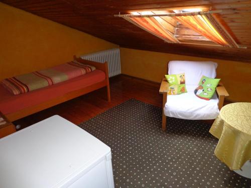 a attic room with a bed and two chairs at Pension Schamberger in Neukirchen beim Heiligen Blut