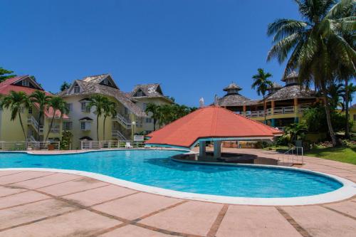 ein Resort-Pool mit einem roten Sonnenschirm und Palmen in der Unterkunft Hillview At Mystic Ridge in Ocho Rios