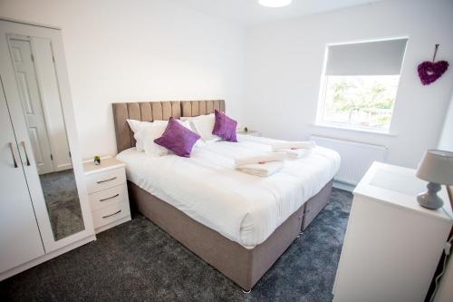 a bedroom with a large bed with purple pillows at Lovely 3 Bedroom House - Close to all attractions - Free Parking in Tamworth