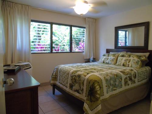 a bedroom with a bed and a desk and windows at Aloha KAI - Resort Condo in Kihei