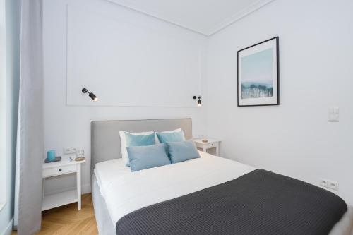 - une chambre blanche avec un lit et des oreillers bleus dans l'établissement Gdansk Old Town ul. Sw. Ducha 68 Apartments, à Gdańsk