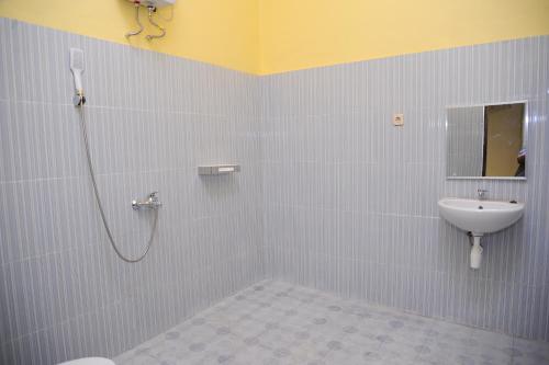 a bathroom with a shower and a toilet and a sink at Rumah Eyang Guest House in Banyuwangi