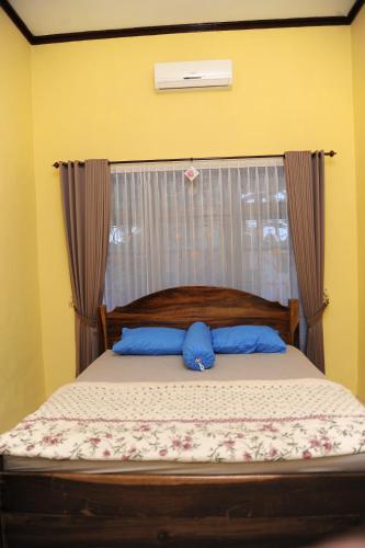 a bed with two blue pillows on top of it at Rumah Eyang Guest House in Banyuwangi