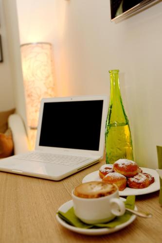 un computer portatile appoggiato su un tavolo con ciambelle e una tazza di caffè di Hotel Principe a Rimini