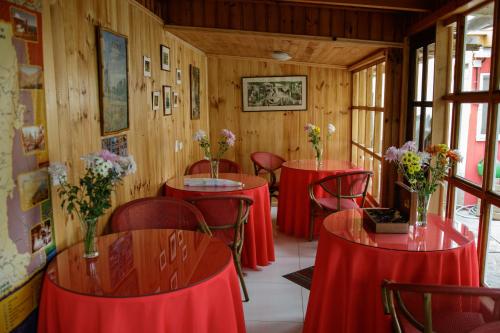 ein Zimmer mit roten Tischen und Stühlen mit Blumen darauf in der Unterkunft Hostal El Conquistador in Los Vilos