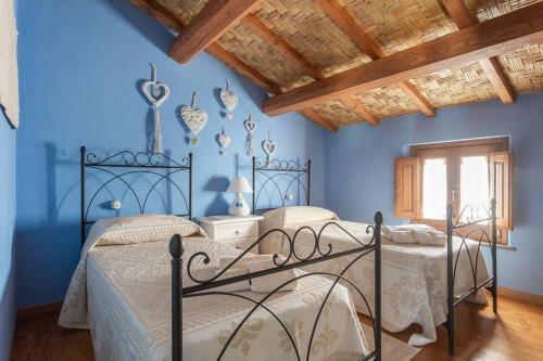 NurachiにあるAntica dimora dell'Arcolaioの青い壁と木製の天井が特徴の客室で、ベッド2台が備わります。