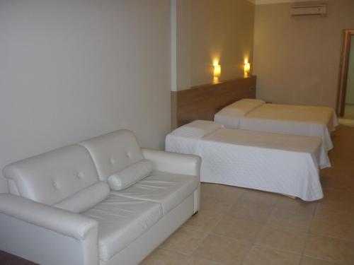 a living room with a couch and two beds at De Rose Praia Hotel in Torres