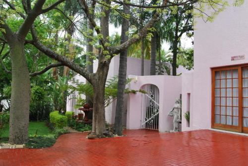 a white house with trees and a red brick driveway at Ronique's Guest House in Rustenburg