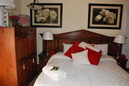 a bedroom with a bed with red and white pillows at Ronique's Guest House in Rustenburg