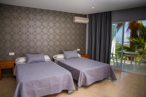 a hotel room with two beds and a balcony at Hotel Salambina in Salobreña